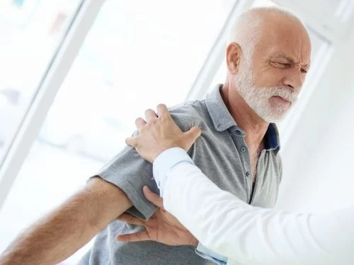 Scopri i sintomi e le cause della lussazione alla spalla! Medico visita uomo sofferente a causa di un dolore alla spalla
