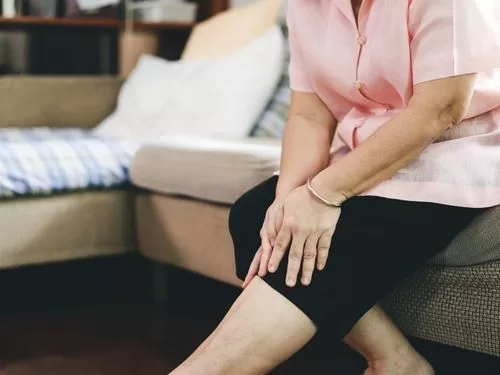 Donna si tocca il ginocchio a causa di un dolore