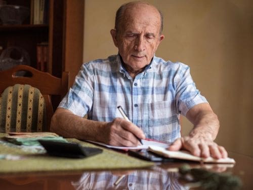 Il Morbo di Parkinson si sviluppa principalmente in una fascia d'età particolare: scopri quale. Signore anziano scrive su un foglio di carta