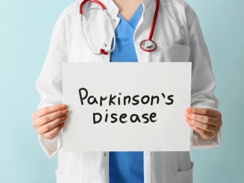 Scopri cos'è il Morbo di Parkinson. Illustrazione di un medico che mantiene un foglio con scritto "Parkinson's Disease"